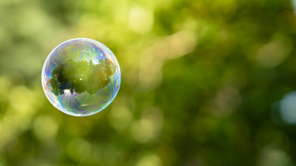 House reflection in soap bubble on green, blurred background. Dream home. 