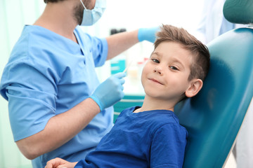Dentist examining little boy's teeth in clinic