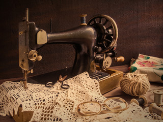Old antique sewing machine, thread, glasses Concept of manual labor, hobbies and history