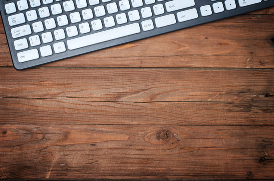 A wooden office table with a keyboard, a copy of the free space. Business background, top view.