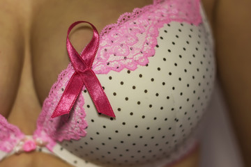 Woman in bra with pink ribbon for awareness of breast cancer.