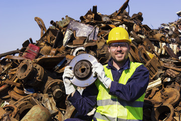 Worker on junkyard hold rotor like shiny trophy - obrazy, fototapety, plakaty