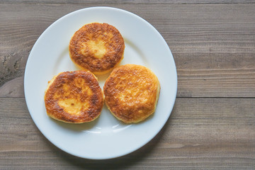 three pancakes on a white plate on a dark table. top view.