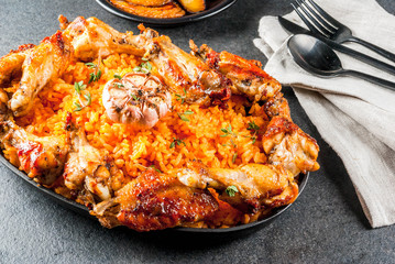 West African national cuisine. Jollof rice with grilled chicken wings and fried bananas plantains.On gray stone table. Copy space