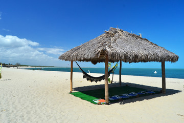 Tenda de palha com uma rede na praia.