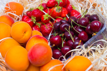 Fruits in a basket of apricots, strawberries and sweet cherries. Summer basket with vitamins
