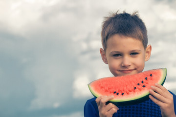 Happy child eating watermelon outdoors
