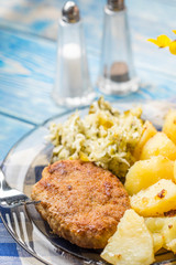 Fried pork chop with boiled potatoes and salad.