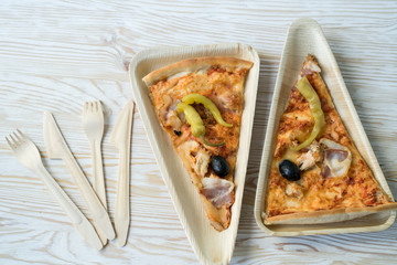 A slices of pizza is on a wooden plate.