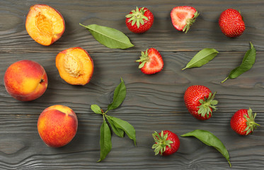 peach fruit with strawberry and green leaf on dark wooden background. top view with copy space