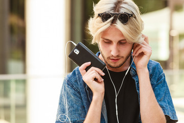 Hipster man standing with earphones talking on phone