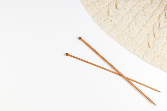 Knitting and pair of wooden knitting needles on white background