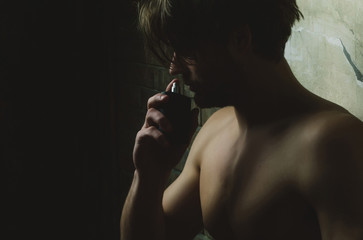 man with naked chest smelling perfume aroma