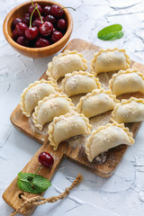 Homemade dumplings with cherries on a wooden board.