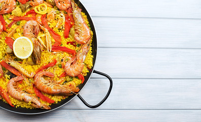From above paella dish in a pot containing rice and vegetables with seafood. Copy space.