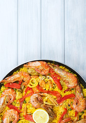 From above paella dish in a pot containing rice and vegetables with seafood. Copy space.