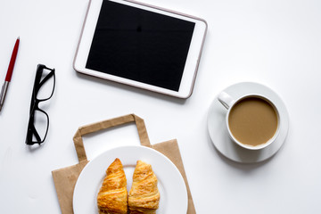 Business lunch with croissant and tablet on white table top view