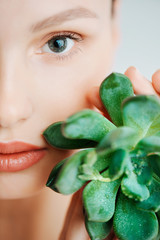Portrait of a beautiful young brunette woman with green leaf in his hand in the studio, the concept of beauty and health