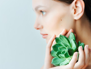 Portrait of a beautiful young brunette woman with green leaf in his hand in the studio, the concept of beauty and health
