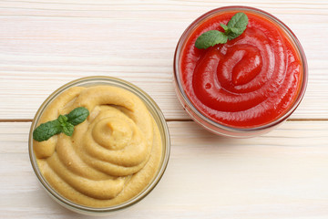 mustard ketchup in glass bowl on white wooden background. Top view.