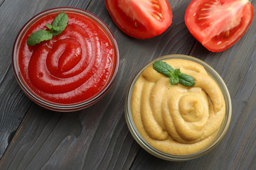 mustard ketchup in glass bowl on dark wooden background. Top view.