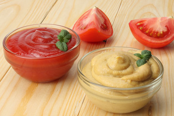 mustard ketchup in glass bowl on wooden background.