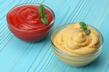 mustard ketchup in glass bowl on blue wooden background.