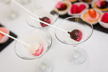 Colorful cake pops in the metal wineglasses on a wooden table