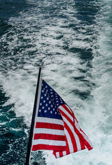 American Flag on stern of yacht against boat wake