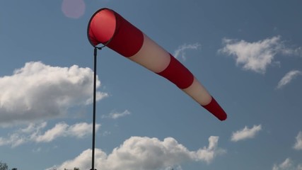 Moving air sleeve windsock show direction of wind blowing near helicopter landing place site on background of blue sky. Static shot.