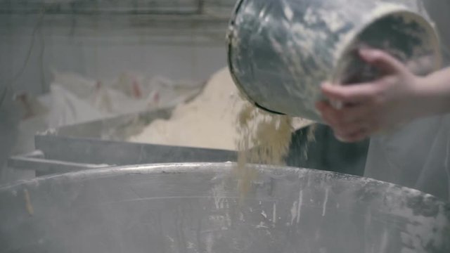 Woman pours the flour into a kneader