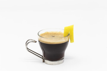 Espresso in the glass cup with lemon peel isolated on white background