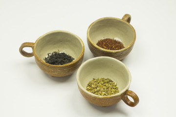 Closeup of three brown clay bowls with tea leaves.