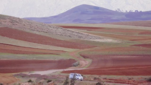 White van passing by the road of the colorful mountains of Peru, Public transportantion on andean mountains.	