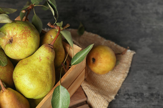 Fresh pears in crate on grey background