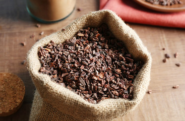 Bag with cocoa nibs on wooden table
