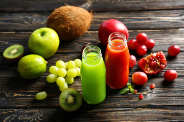 Delicious juice in bottles with ingredients on wooden background