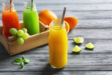 Bottles of delicious juice with ingredients on wooden background