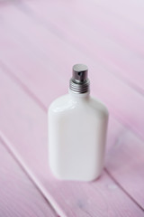 Parfume white bottle on light pink wooden backdrop