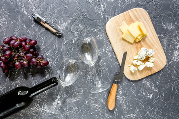 Bottle of red wine with cheese and grape aperitive on grey stone table background top view
