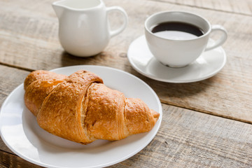 croissant and cup of coffee on office desk for business breakfast wooden background