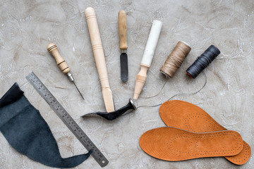Set of cobbler tools on grey stone desk background top view