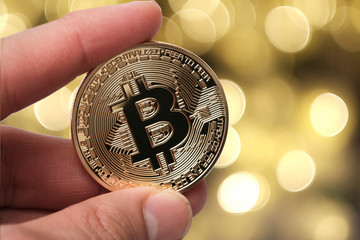 Hand holding golden bitcoin isolated on abstract background