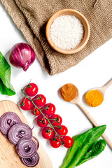 homemade paella ingredients composition with rice, tomato, onion on white table background top view