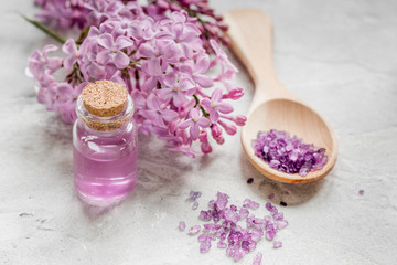 lilac cosmetics with flowers and spa set on stone table background