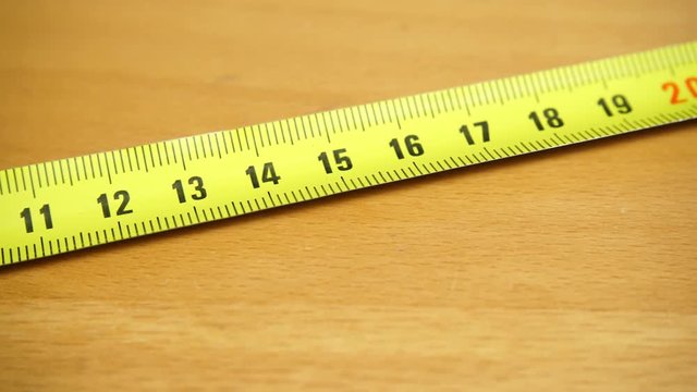 Tape measure on the brown wooden background. Construction, engineering, repair concept. Dolly sliding shot 4K ProRes HQ codec