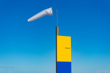 Extended Windsock and beach sign against blue sky on the background