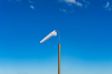 White extended Windsock on wooden pole against blue sky on the background