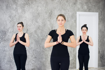 Young sportive trio group of girls are practicing yoga exercises in the studio