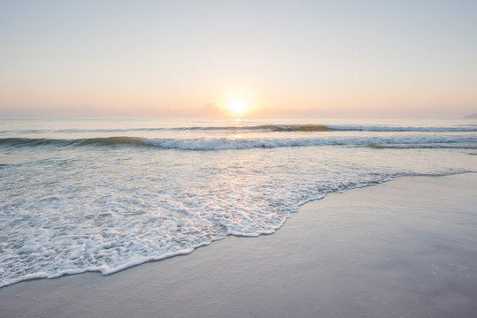 Fototapeta Piękny zachód słońca i delikatna fala na płytkiej plaży